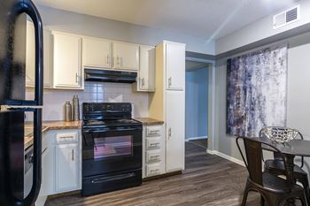 A kitchen with a black refrigerator and black oven.